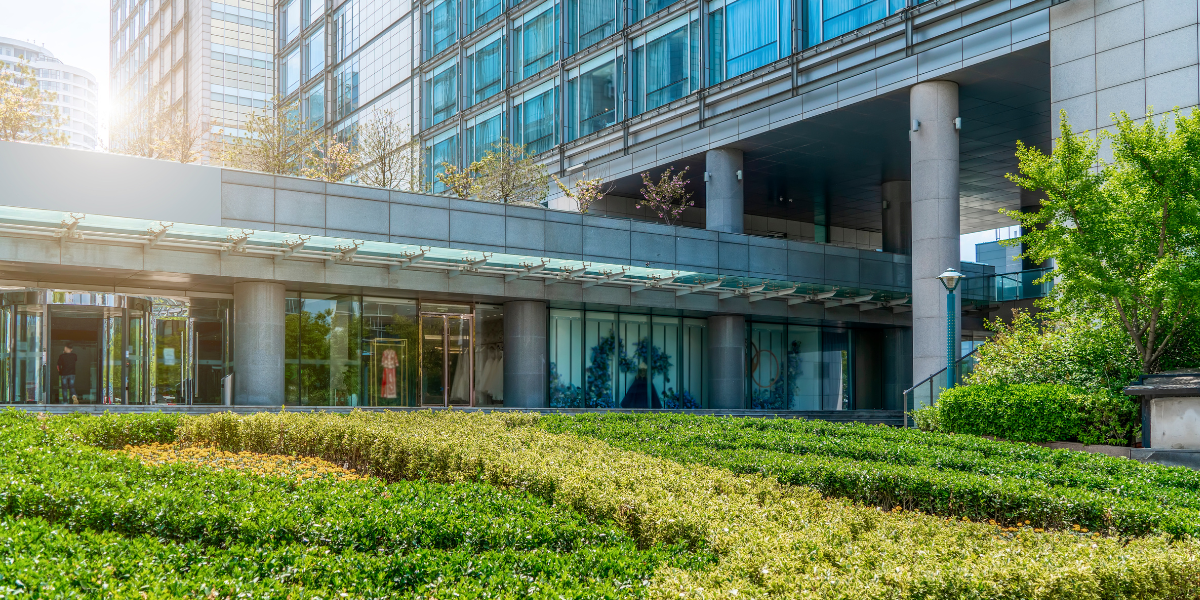 Automated energy management - Two people sit at a desk with a laptop, model wind turbine, hard hat, and solar panel, holding a clipboard displaying an energy efficiency chart with coloured ratings from A to G.