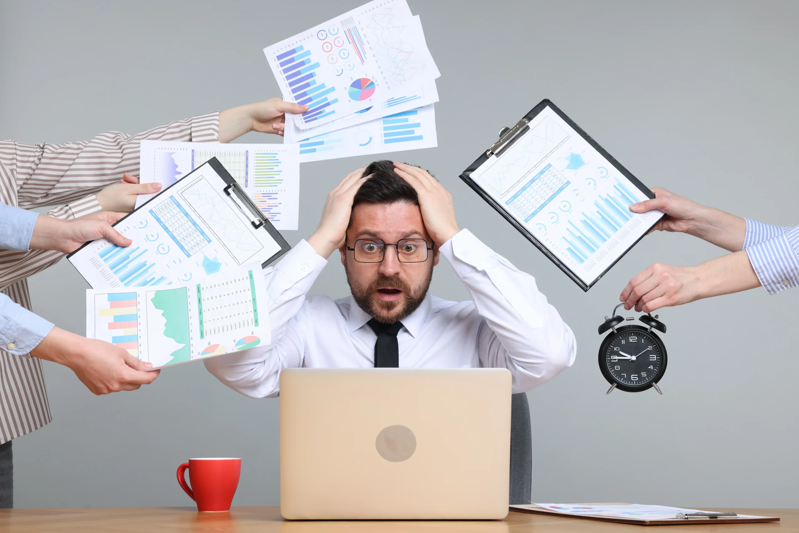 Automated energy management - Two people sit at a desk with a laptop, model wind turbine, hard hat, and solar panel, holding a clipboard displaying an energy efficiency chart with coloured ratings from A to G. Automated energy management - Two people sit at a desk with a laptop, model wind turbine, hard hat, and solar panel, holding a clipboard displaying an energy efficiency chart with coloured ratings from A to G.