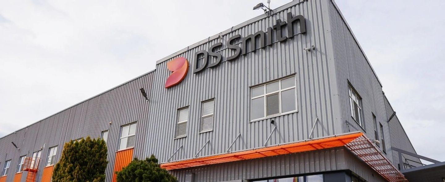 Automated energy management - A large, grey industrial building with the DS Smith logo and name on the exterior wall; windows and orange awnings are visible, along with some trees beside the structure.